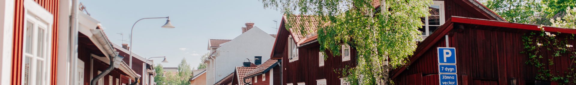 Parkerade bilar längs med lummig gågata i centrala Falun
