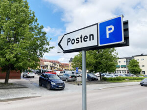 En skylt med texten Posten P pekar mot en parkeringsplats.