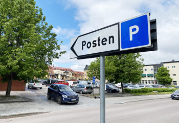 En skylt med texten Posten P pekar mot en parkeringsplats.